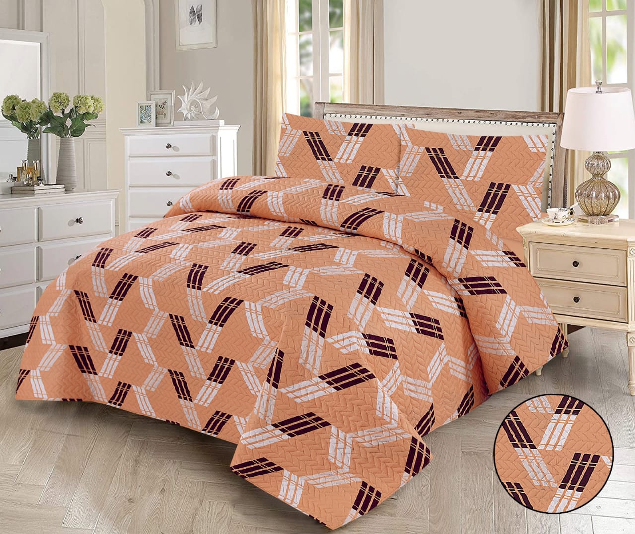 Patterned orange quilt on a bed in a bedroom setting with furniture and decor.