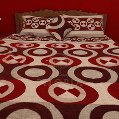 Red and white patterned bedspread on a bed with matching pillows against a red wall.
