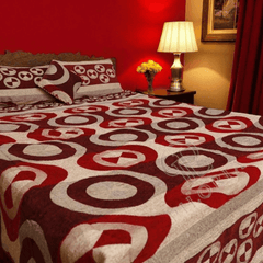 Bed with a red and white patterned comforter in a bedroom setting.