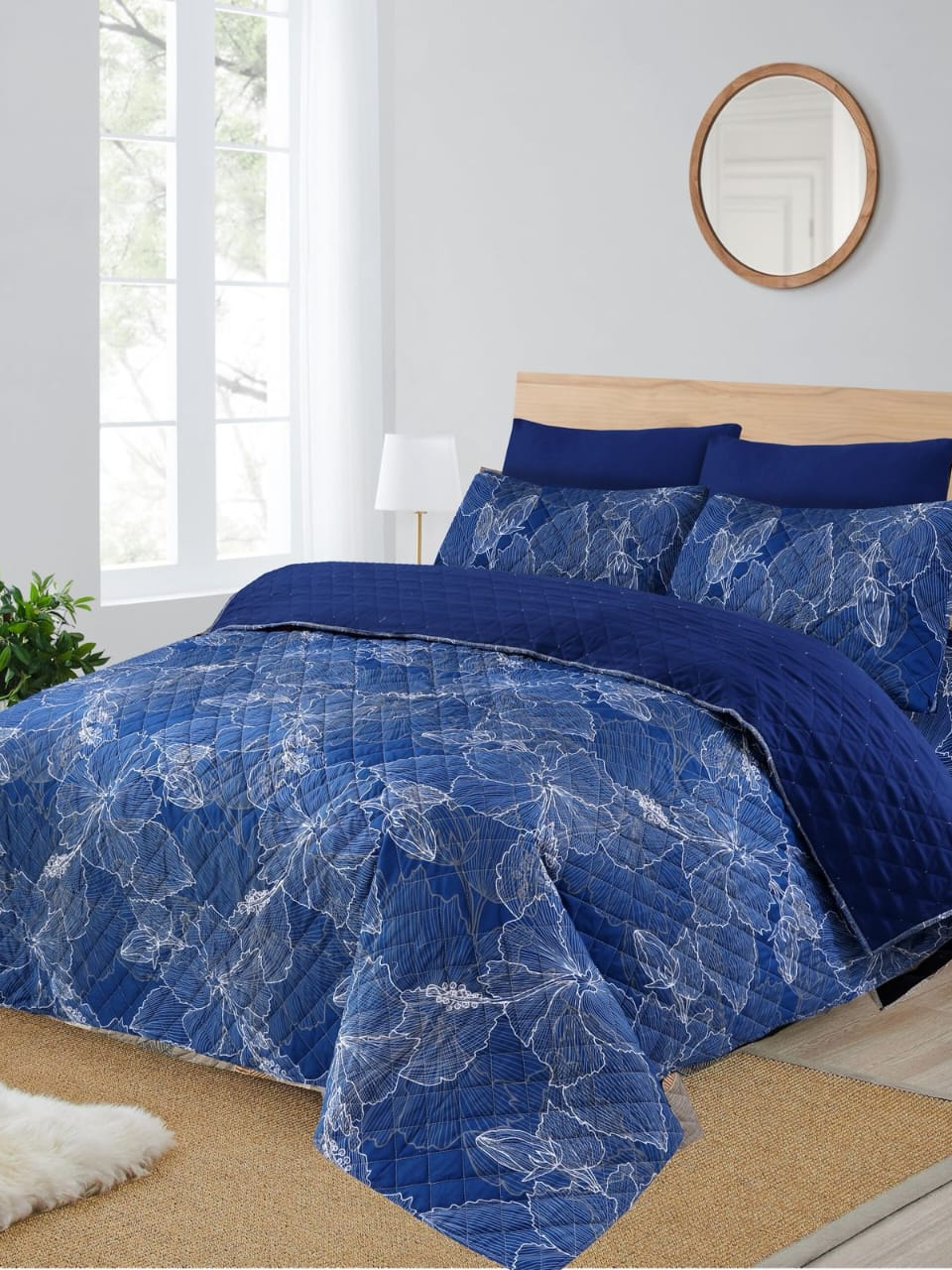 Blue floral-patterned comforter set on a bed in a bright bedroom.