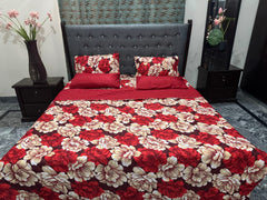 Red and beige floral bedspread on a bed with matching pillows, set against a gray upholstered headboard.