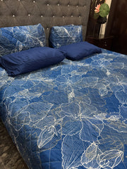 Blue floral patterned bedspread on a bed with matching pillows.