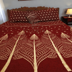Red bedspread with white leaf patterns on a bed in a bedroom.