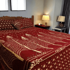 Red and gold patterned bedspread on a bed in a bedroom setting.