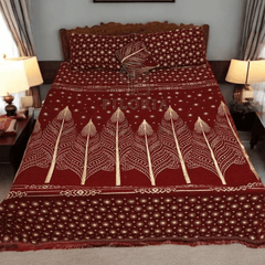 Red and gold patterned bedspread with 'PILORIA' branding on a bed in a room.