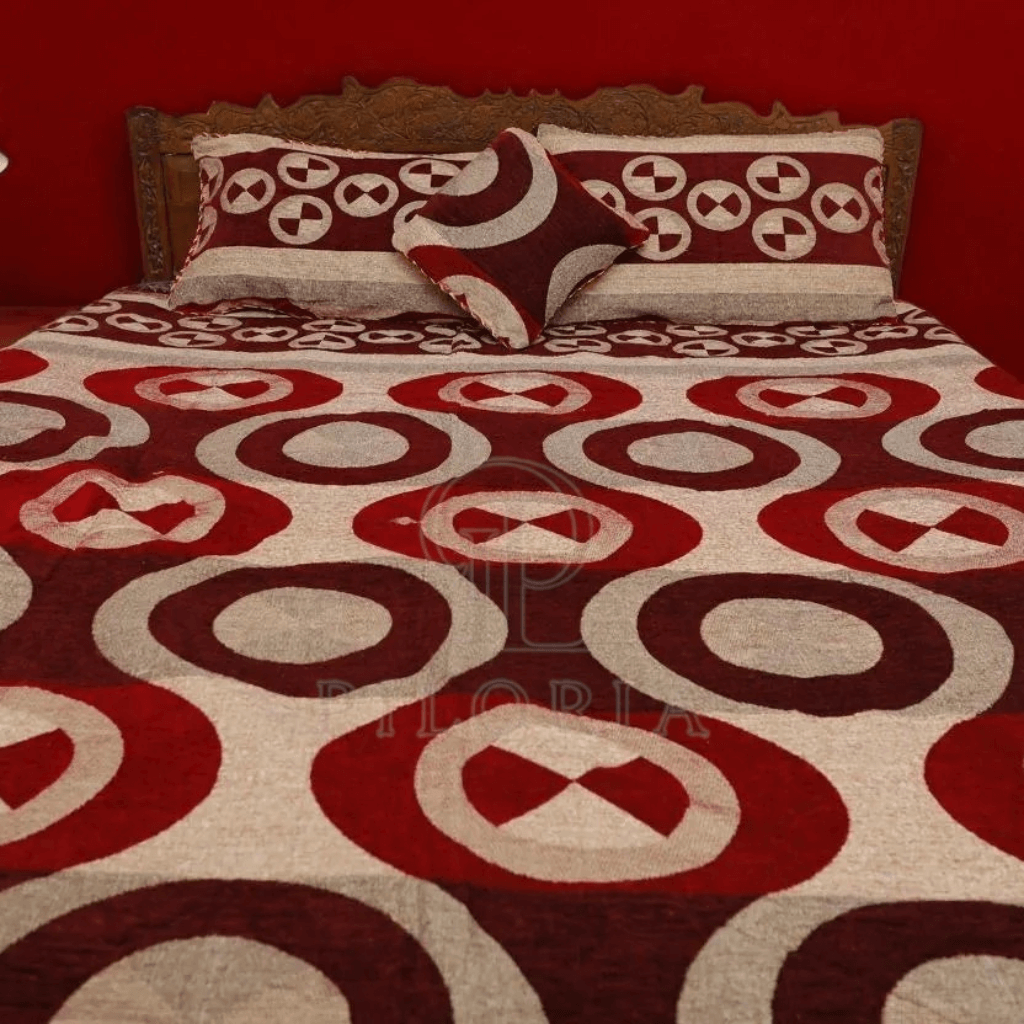 Red and white patterned bedspread on a bed with matching pillows against a red wall.