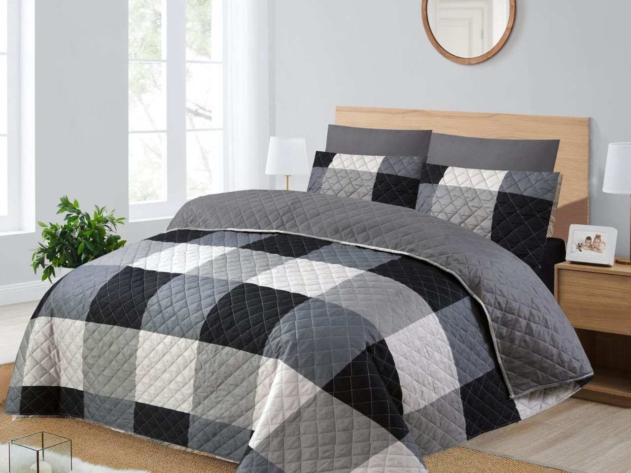 Gray and black checkered quilt set on a bed in a bedroom.