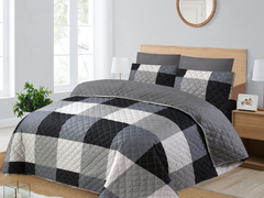 Gray and black checkered quilt set on a bed in a bedroom.