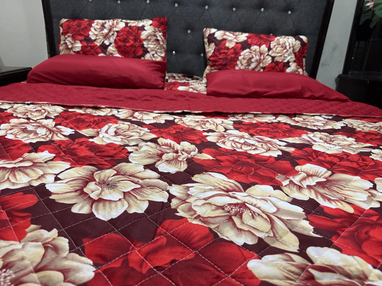 Floral patterned bedspread on a bed with red and beige flowers