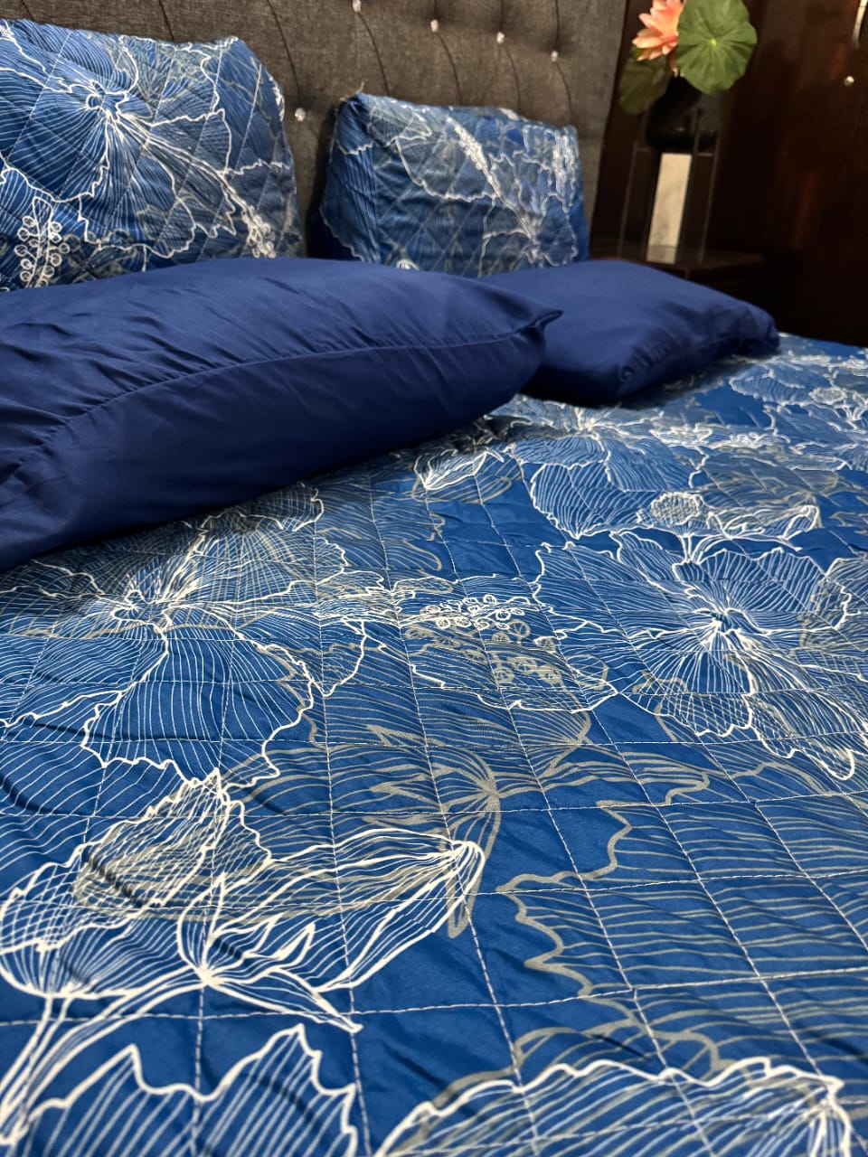 Blue floral patterned comforter on a bed with matching pillows.