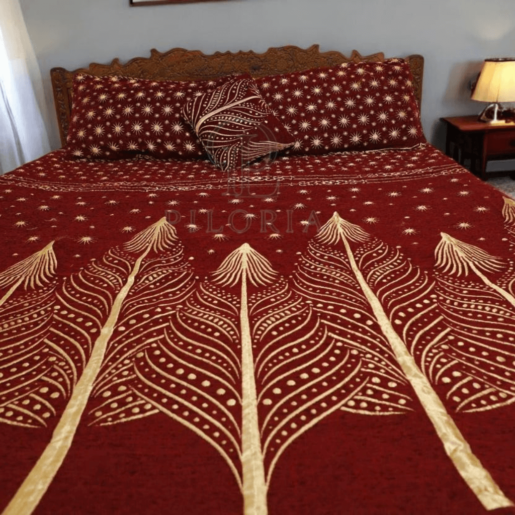 Red bedspread with white leaf patterns on a bed in a bedroom.